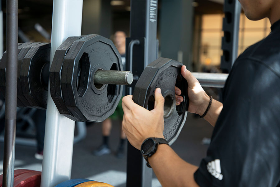 Hands putting weights on to a lifting machine for a workouut