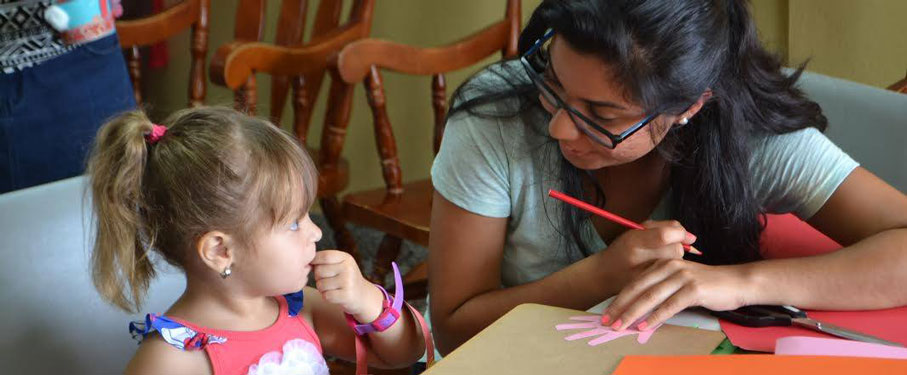 An LMU student working on an art project with a young girl.