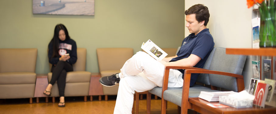 lmu shs student health services male student in shs waiting room reading informational brochure