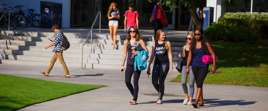 lmu students affairs health wellness four female students walking together in front of Von Der Ahe all holding yoga mats 