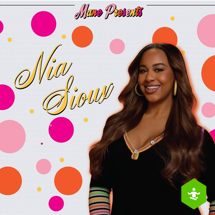 A person with long wavy hair, hoop earrings, and a black top with colorful striped accents stands on the right side. The light gray background is decorated with bright pink, orange, yellow, and pastel pink polka dots. A green hexagonal icon with a white figure appears in the bottom-right corner.