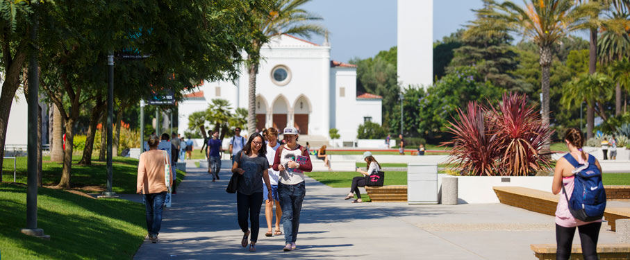 Students walking around campus with Sacred Heart Chapel in the background