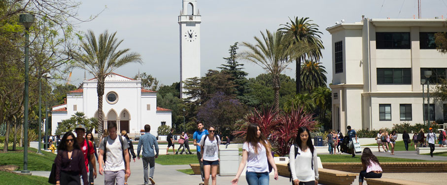 Students walking across LMU campus with Sacred Heart Chapel and Malone Student Center in the background