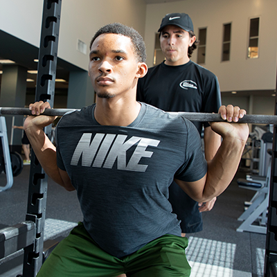 Two students work out in the Burns Recreation Center lifting weights.