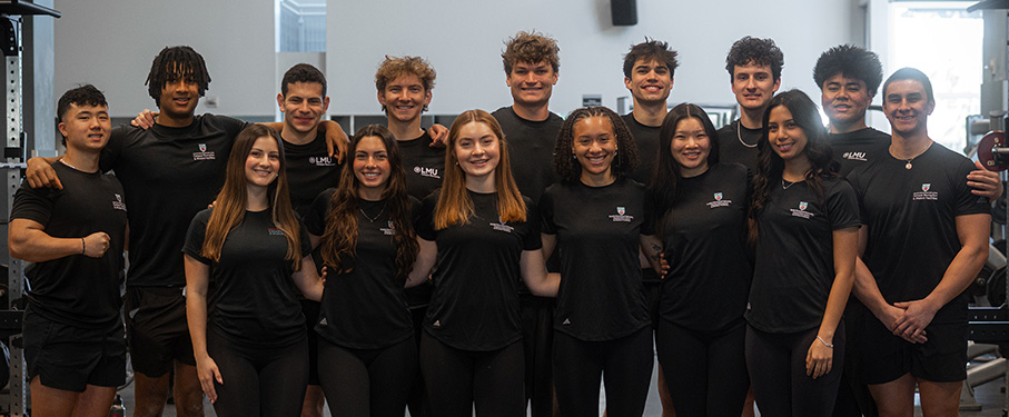 A group shot of student personal trainers in the weight room wearing all black.