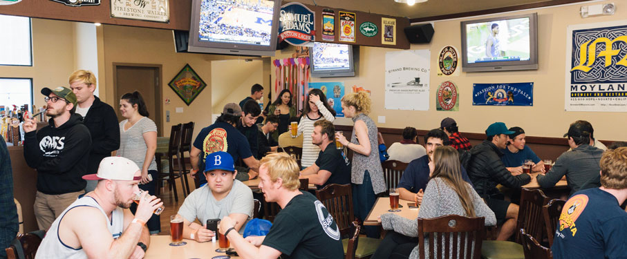 Students siting at tables and standing having drinks inside The Loft at LMU