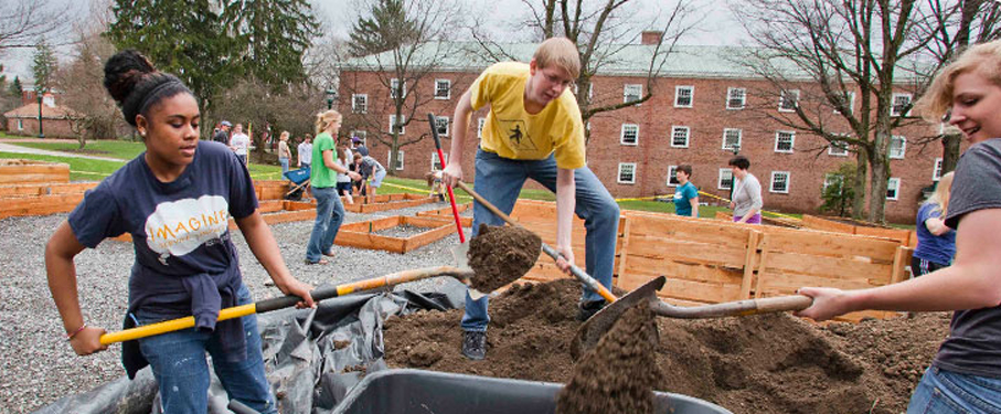 LMU students shoveling dirt in a garden.
