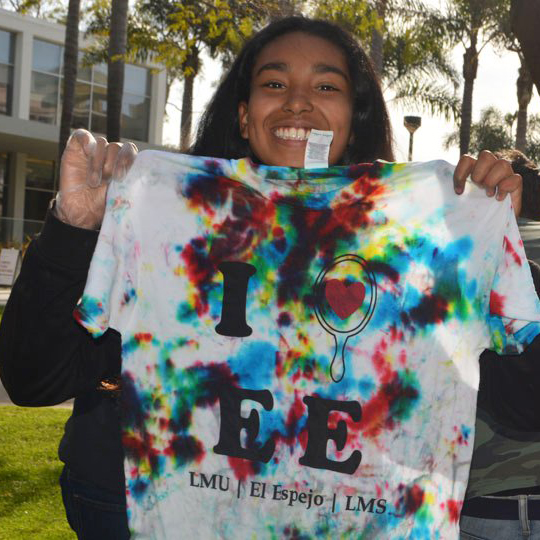 a female member of El Espejo holding up an El Espejo tshirt