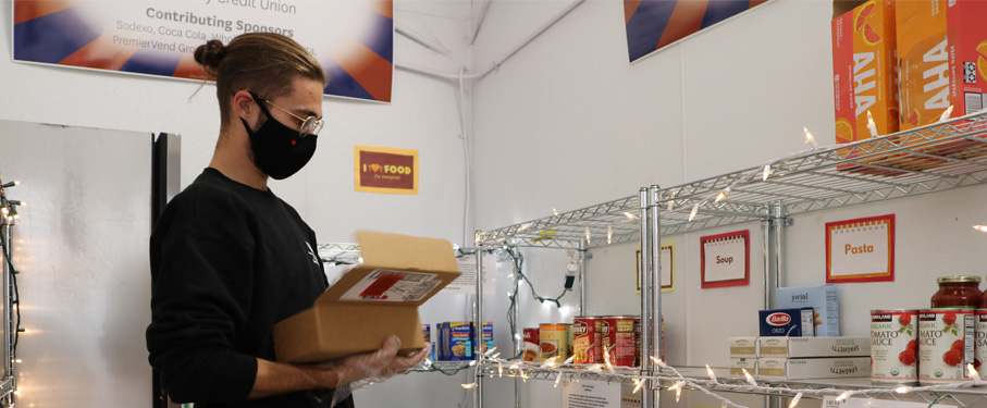 a student placing items on the shelves of the food pantry