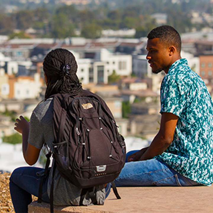 Two students sit on a bench overlooking the bluff.