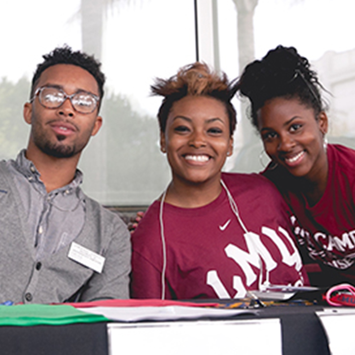 Students gather at a table outside for an event.