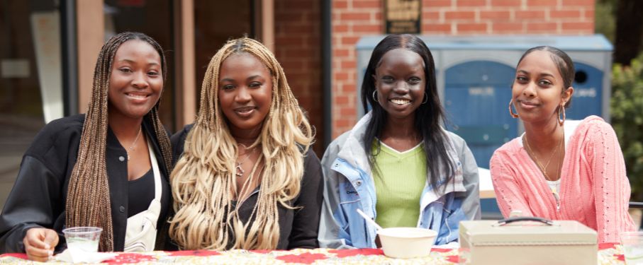 A group of female students pose at a table outside the Mbgoni Spot.