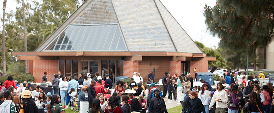A wide angle exterior shot of a group gathered outside of the Mbongi Spot.