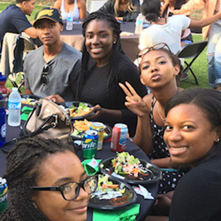 Students gather at a table outside during a welcome event.