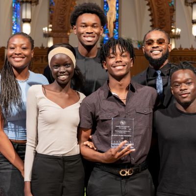 Students stand on stage in the chapel after receiving a student organization award.