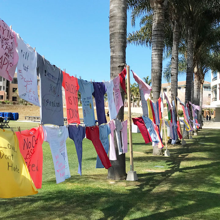 Clothesline tied between two trees holding multi colored shirts