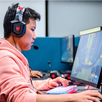 A student playing video games at a computer with headphones on