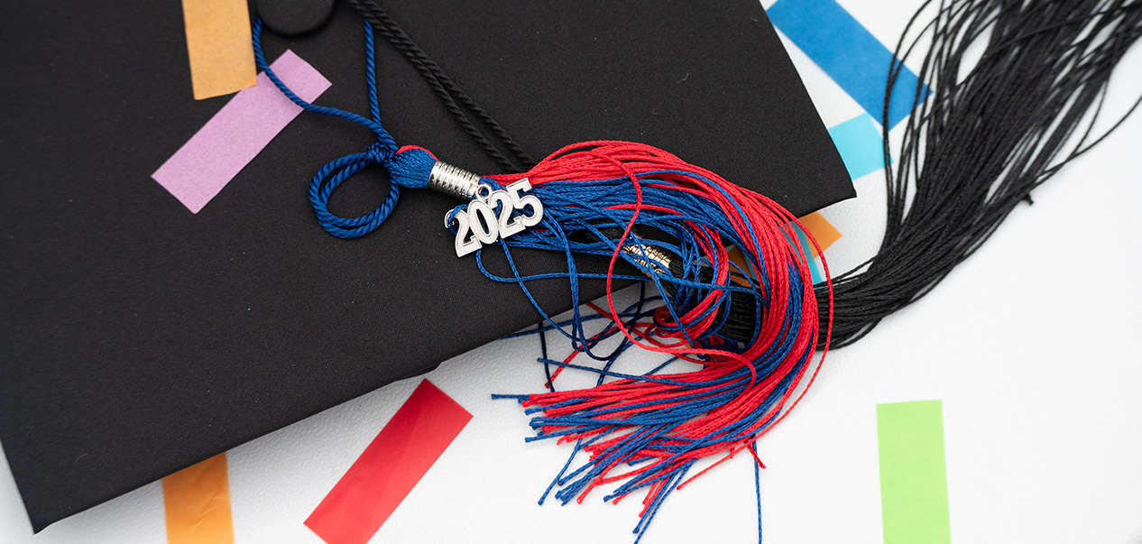 A graduation cap on top of a table with confetti and a tassel that reads 2025.