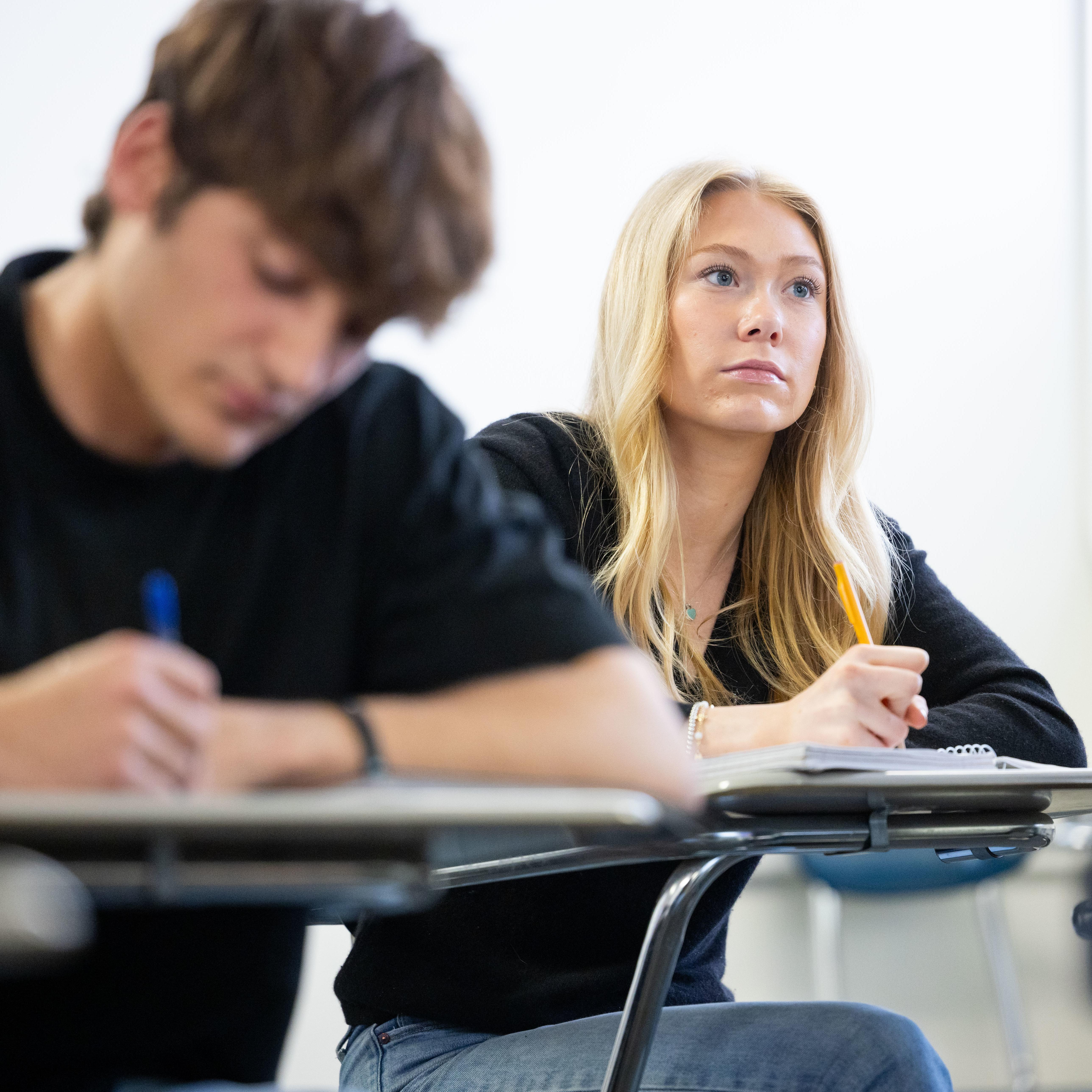 Two students sit inside a classroom during a classroom lecture.