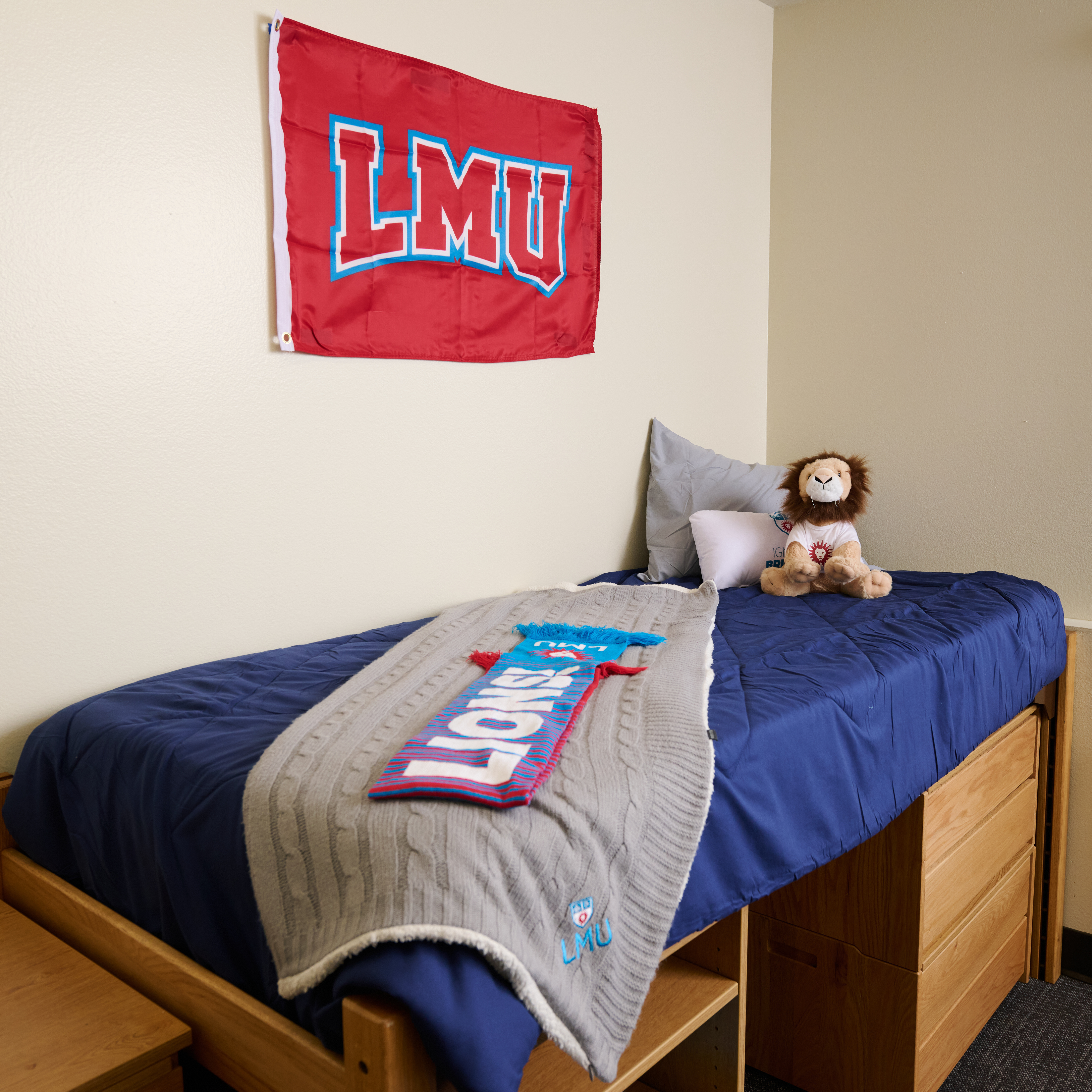 An interior shot inside a residence hall including a bed with a blue comforter and a stuffed Lion.