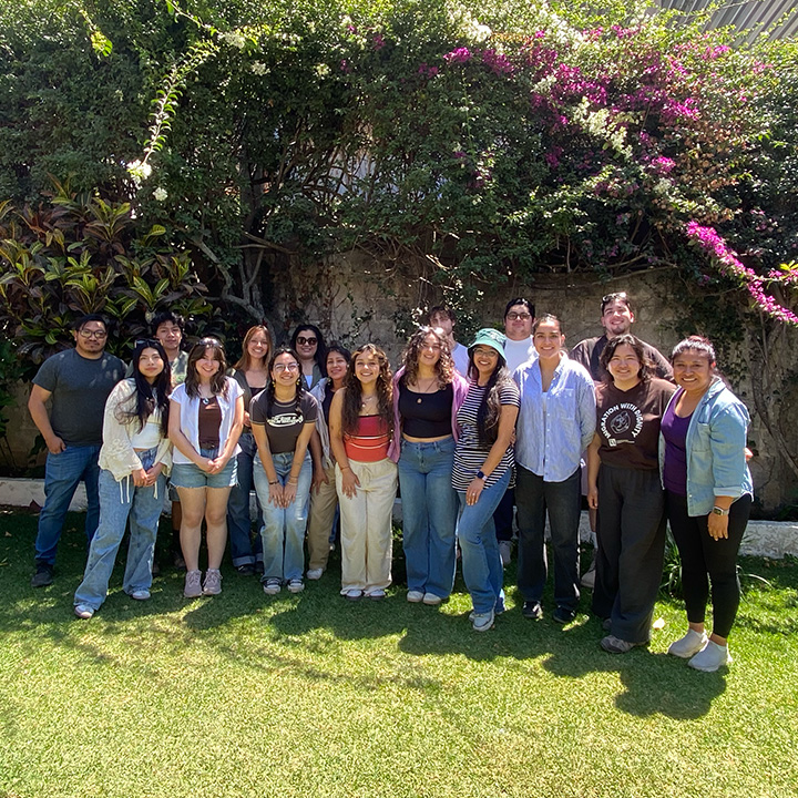 Students gather with locals outside on green grass in Guatemala.
