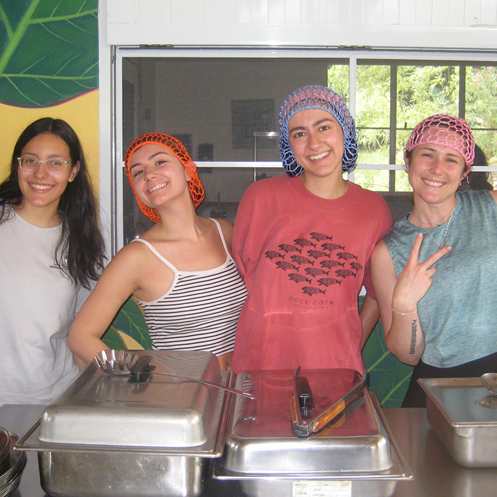 Students and staff pose inside with hairnets on preparing a meal on a immersion trip in Puerto Rico.
