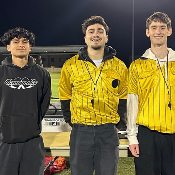 Three students pose in sports gear outside for an intramural sports game.
