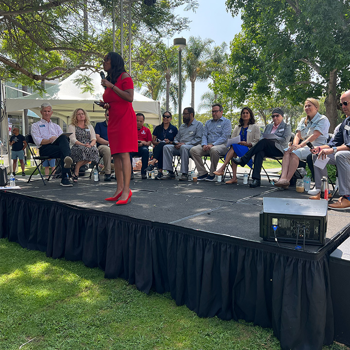 Student Affairs leadership team presents outside on a stage to parents and families during orientation.