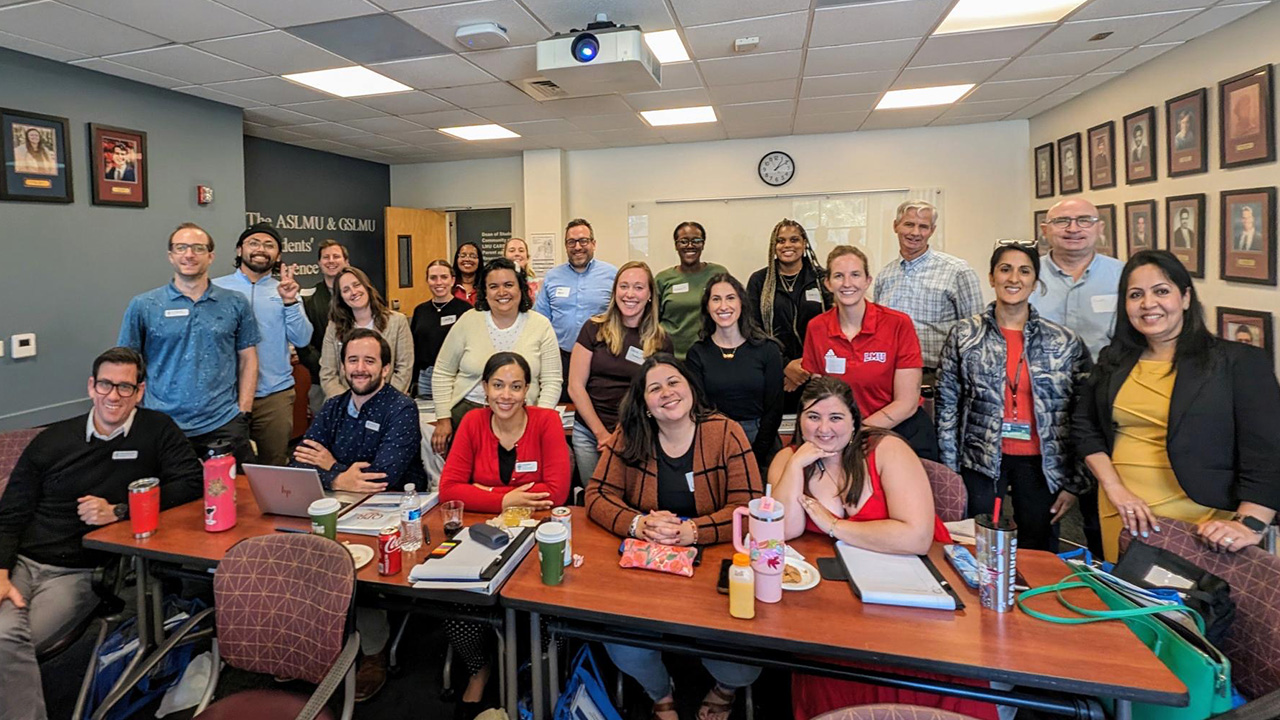 Staff gathers inside a conference room after a meeting for a photo.
