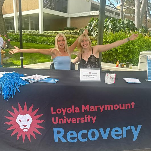 Two students pose at a table outside at Wellness Wednesday with Recovery at LMU resources.