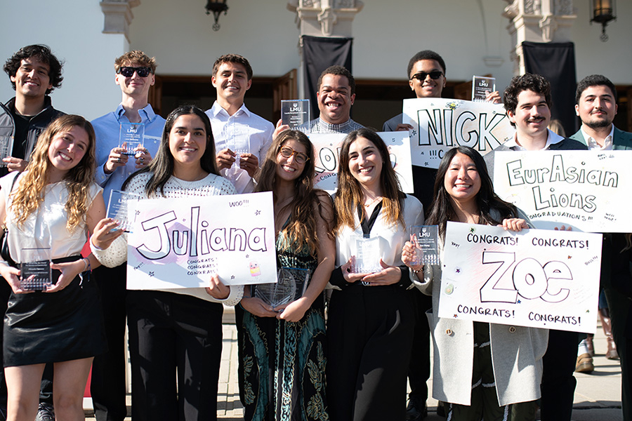 Students hold posters and plaques standing outside of Sacred Heart Chapel for the annual Student Academic, Service, and Leadership Awards.