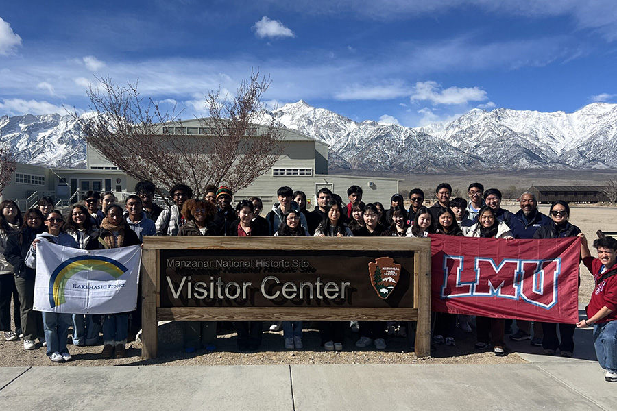 Students stand outside with university flags in Japan for the Tomodachi Scholars program.