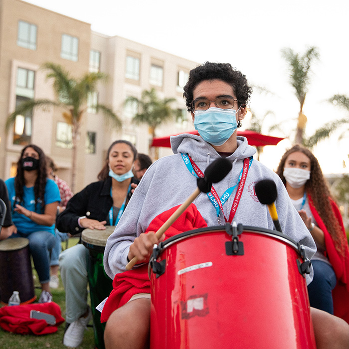 Students outside at an event learning drumming.