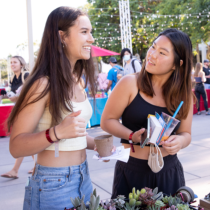Two female students putting together succulents pots at an event outside.