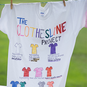 A photo of a white t-shirt hanging on a clothesline explaining the Clothesline Project