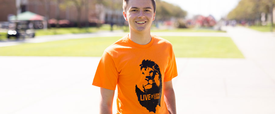 A student wearing an orange Live the Lion's Code shirt. 