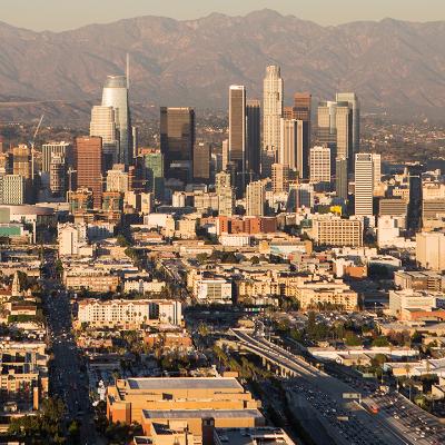 A helicopter aerial shot over downtown Los Angeles with the mountains in the background.