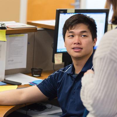 A student staff member talks to a staff member at the front desk in the international student office.