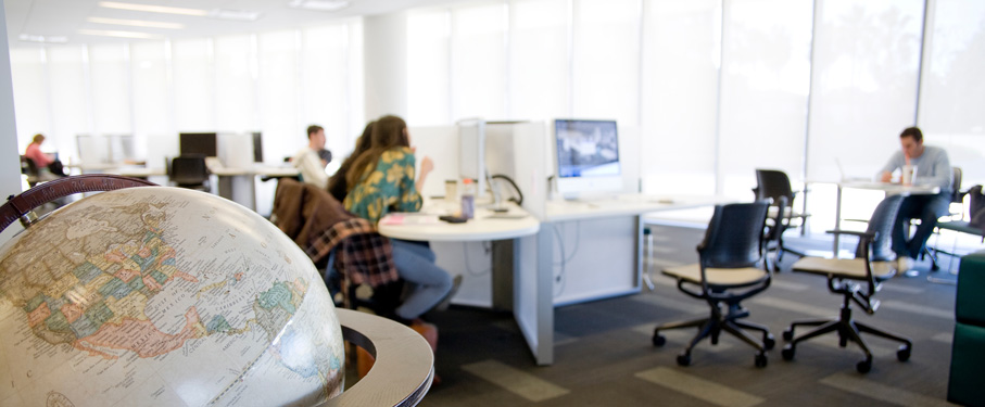A close-up of a globe with students studying in the background.