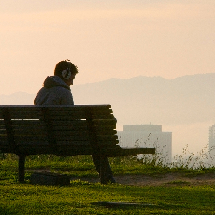 Student sitting alone on a bunch overlooking the bluff