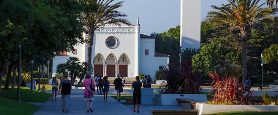 Students walking on Alumni Mall with Sacred Heart Chapel in the background