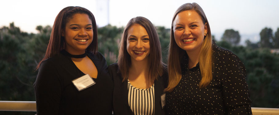 Three transfer students stand together under the sunset outside.