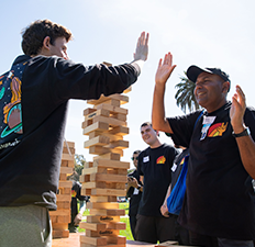 A student and Special Games participant give high fives outside next to a large Jenga game.