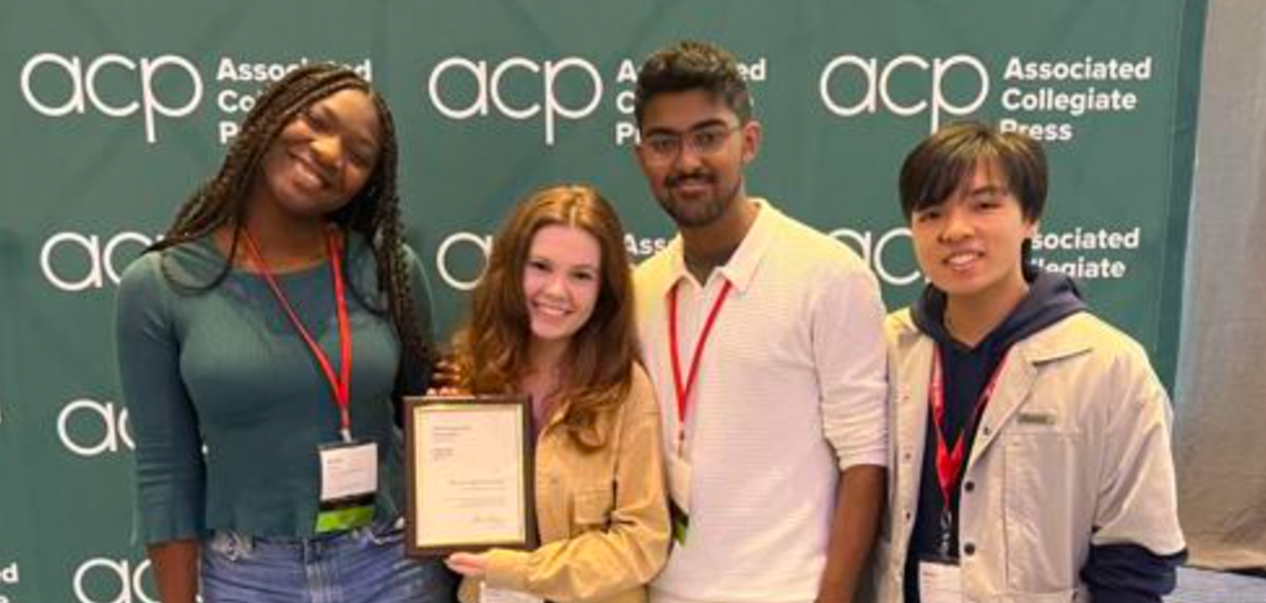 Four students pose with student media awards in front of a green backdrop.