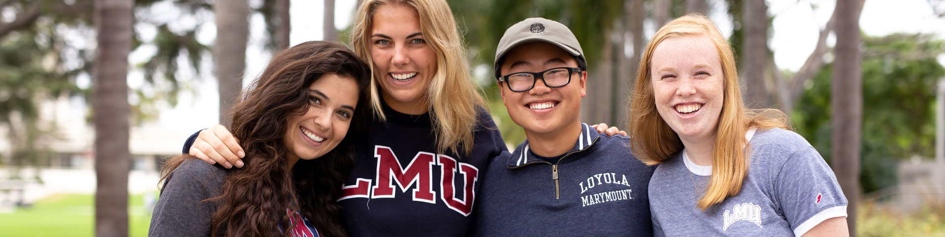 Four students standing together and smiling on Palm Walk